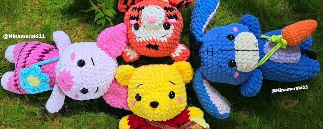 Crocheted animal plush toys on grass with flowers